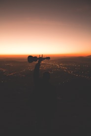 silhouette photography of person holding guitar