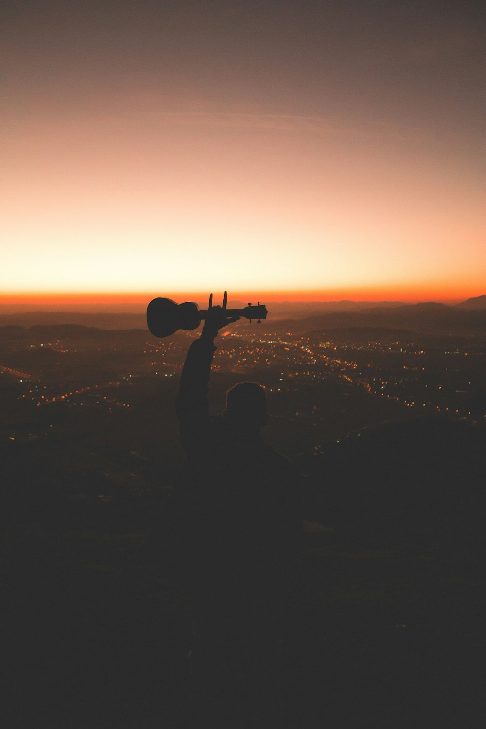 silhouette photography of person holding guitar