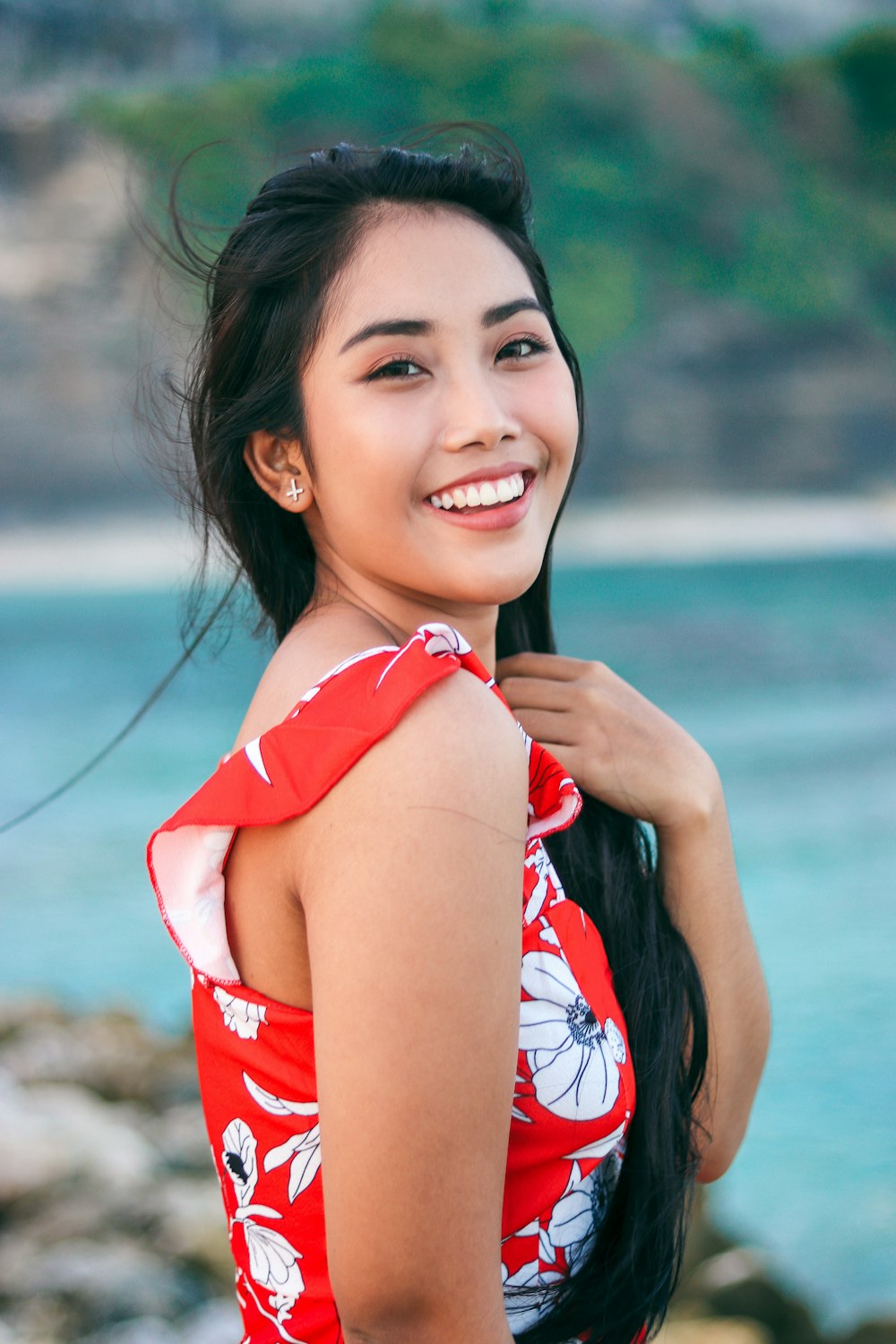 woman wearing white and red floral top across body of water
