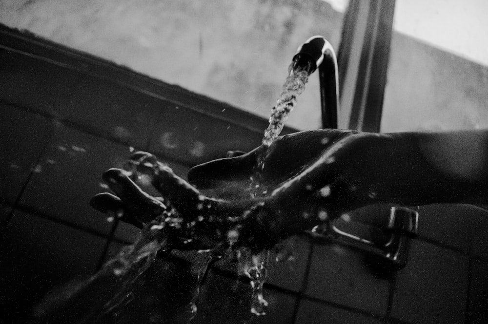 opened faucet and water dropping on human hand