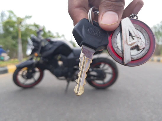 A friendly delivery person handing over a motorcycle key to a happy customer at their doorstep