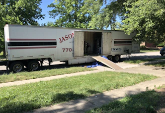 Skilled workers loading household furniture into a moving truck in a residential neighborhood.