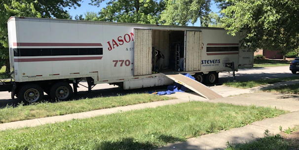 Skilled workers loading household furniture into a moving truck in a residential neighborhood.
