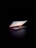 A slightly open laptop is positioned on a dark surface with a dark background. The screen displays a calm scene of the sky during sunset. The light from the screen casts a gentle glow around the laptop.