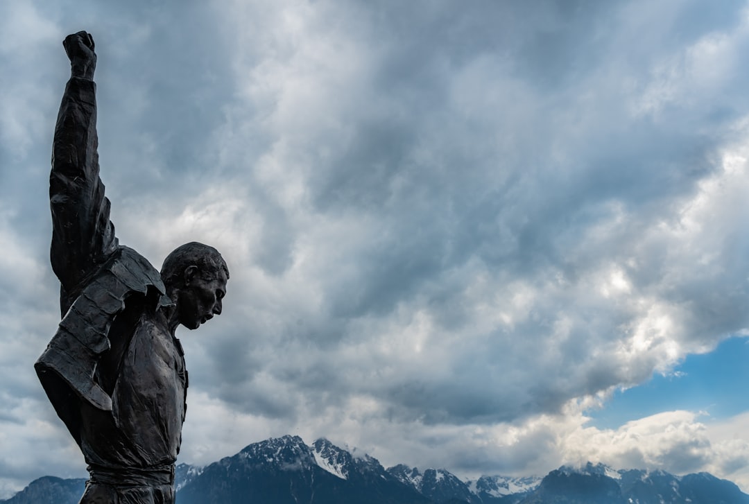 man in jacket statue under white clouds