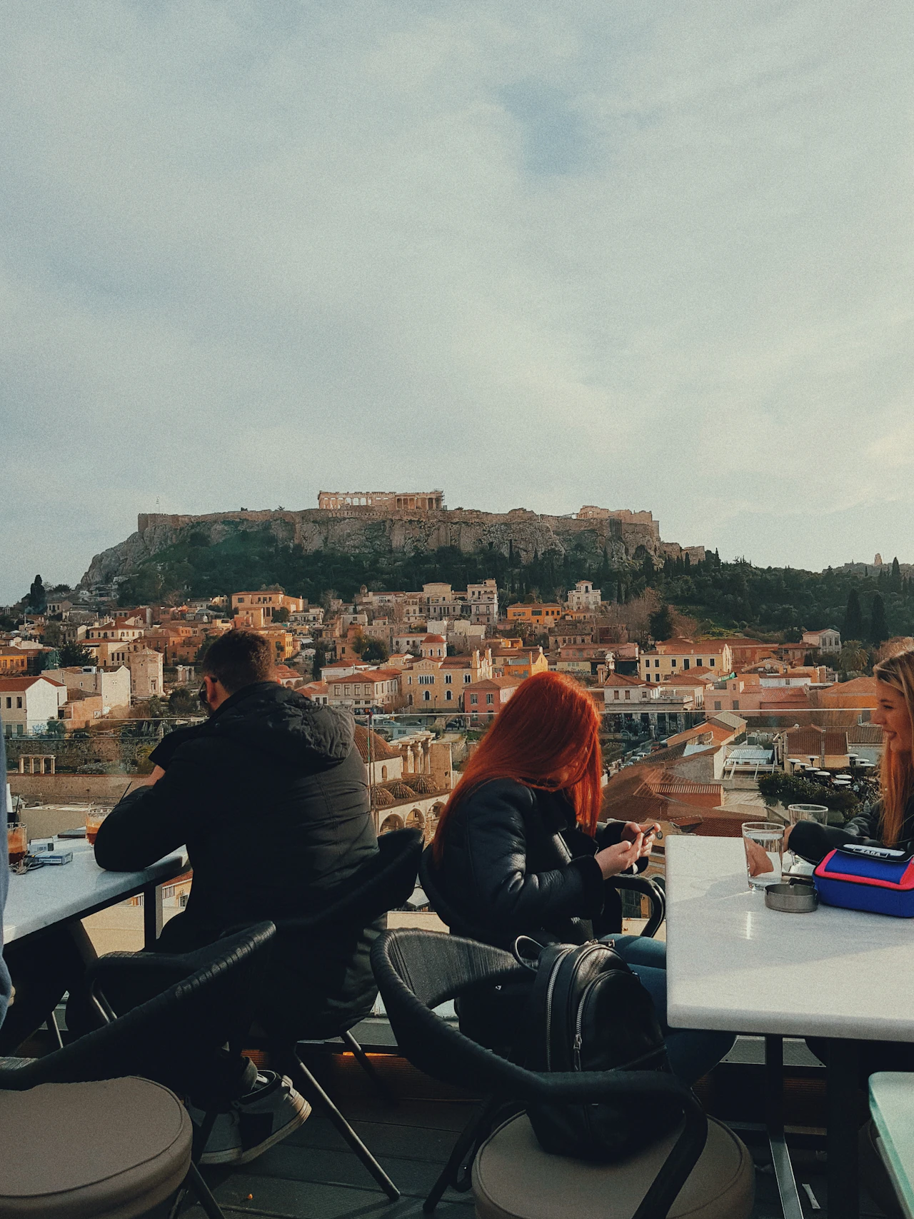 People on an Athens rooftop with an Acropolis view at dusk