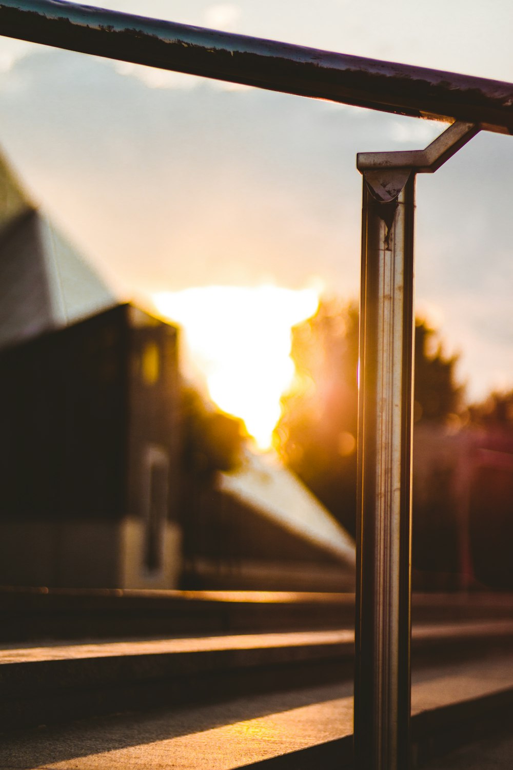 the sun is setting behind a metal railing