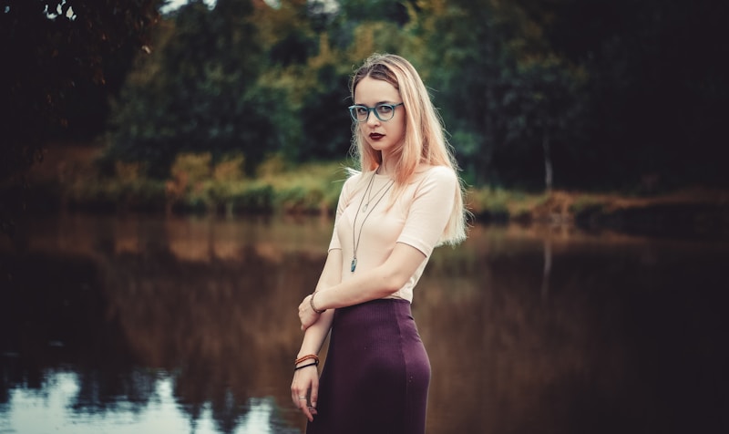 woman standing beside body of water near outdoor during daytime