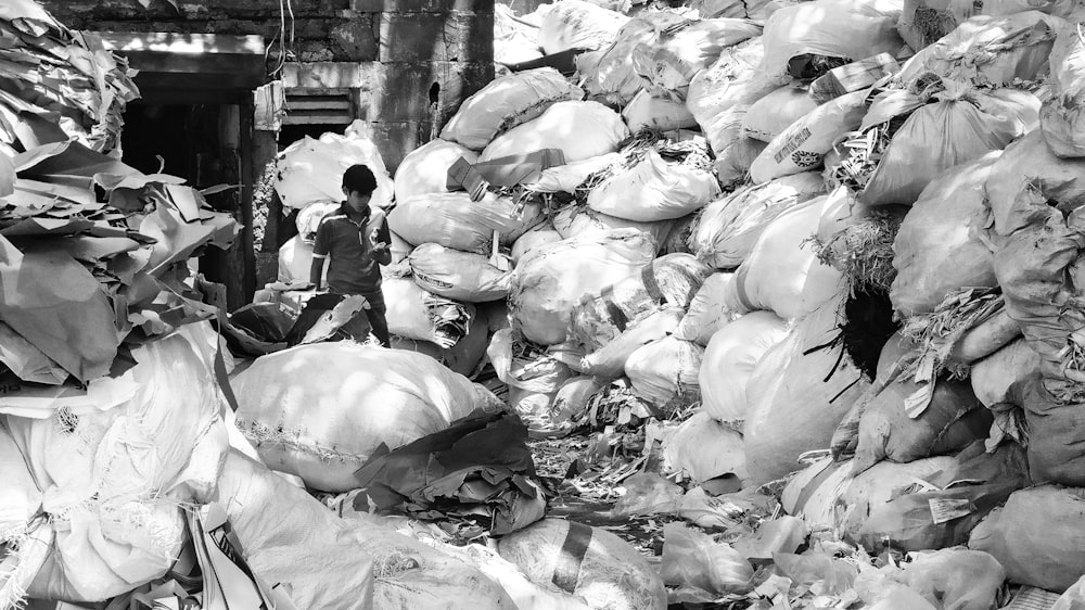 grayscale photo of man standing beside file of sack