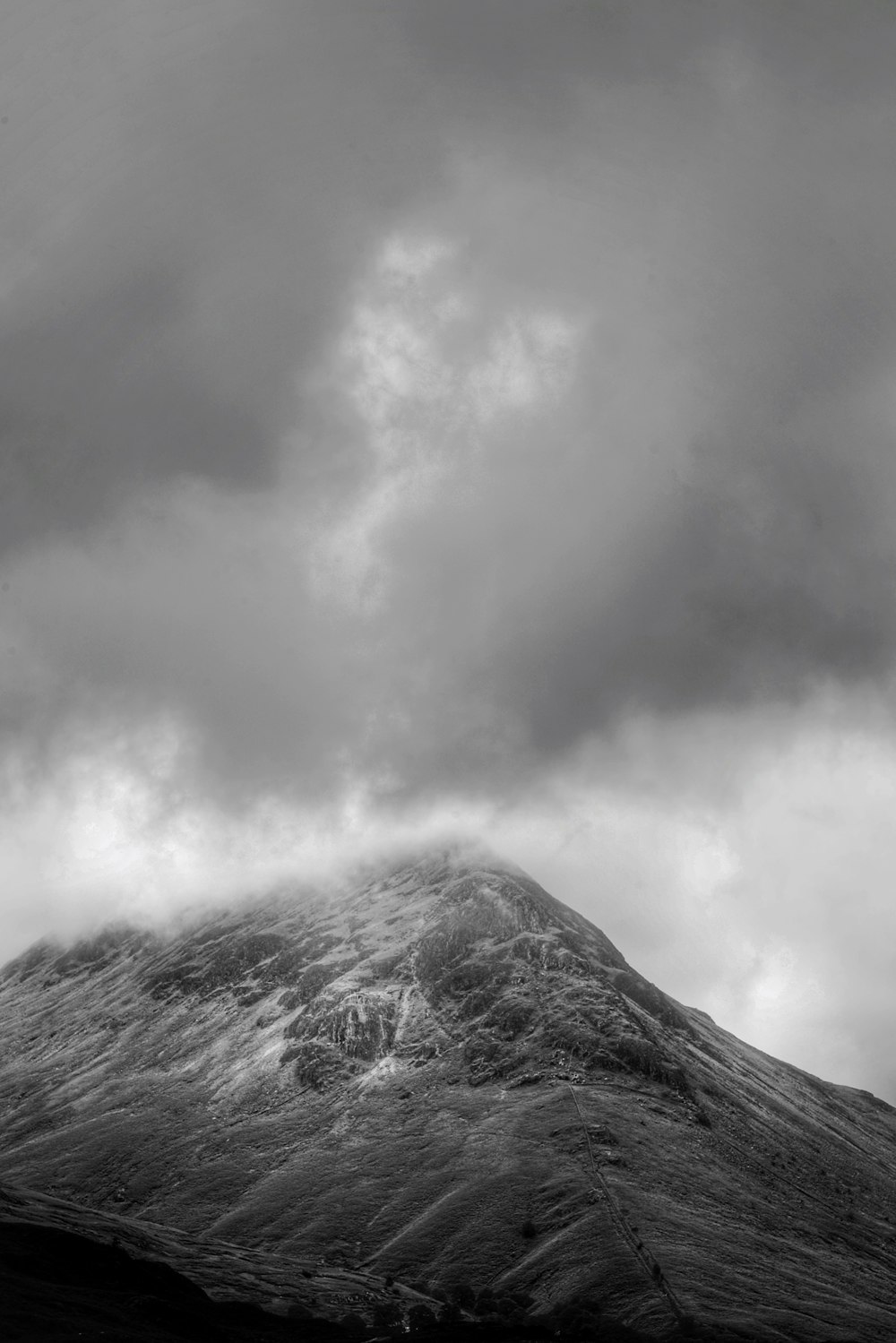 grayscale photography of mountain covered with fogs