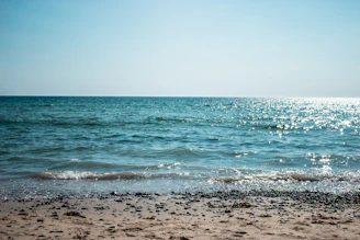 A serene beach scene on the French Riviera, turquoise waves gently lapping against sun-drenched pebbles.