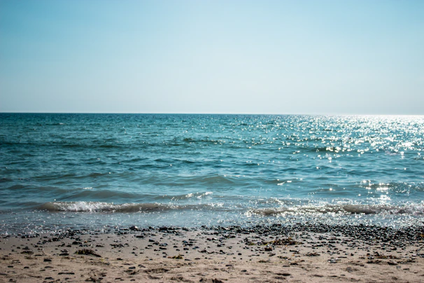 A serene beach scene on the French Riviera, turquoise waves gently lapping against sun-drenched pebbles.
