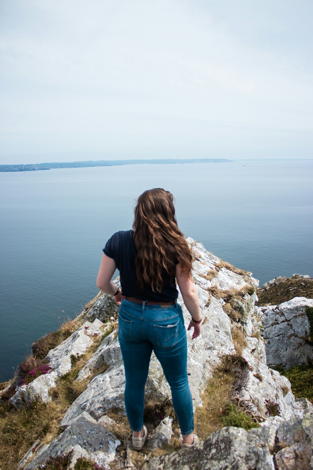 woman wearing black shirt and blue denim jeans standing on rock