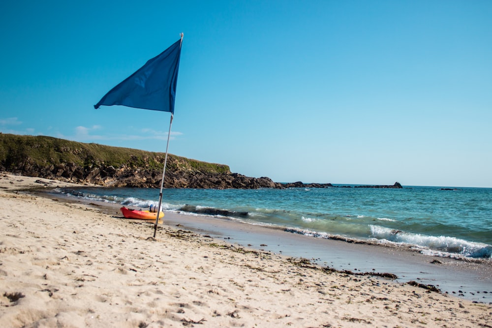 blue flag beside body of water at daytime