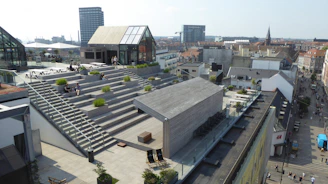 Modern rooftop garden with wooden decking and vibrant plants overlooking Istanbul skyline.