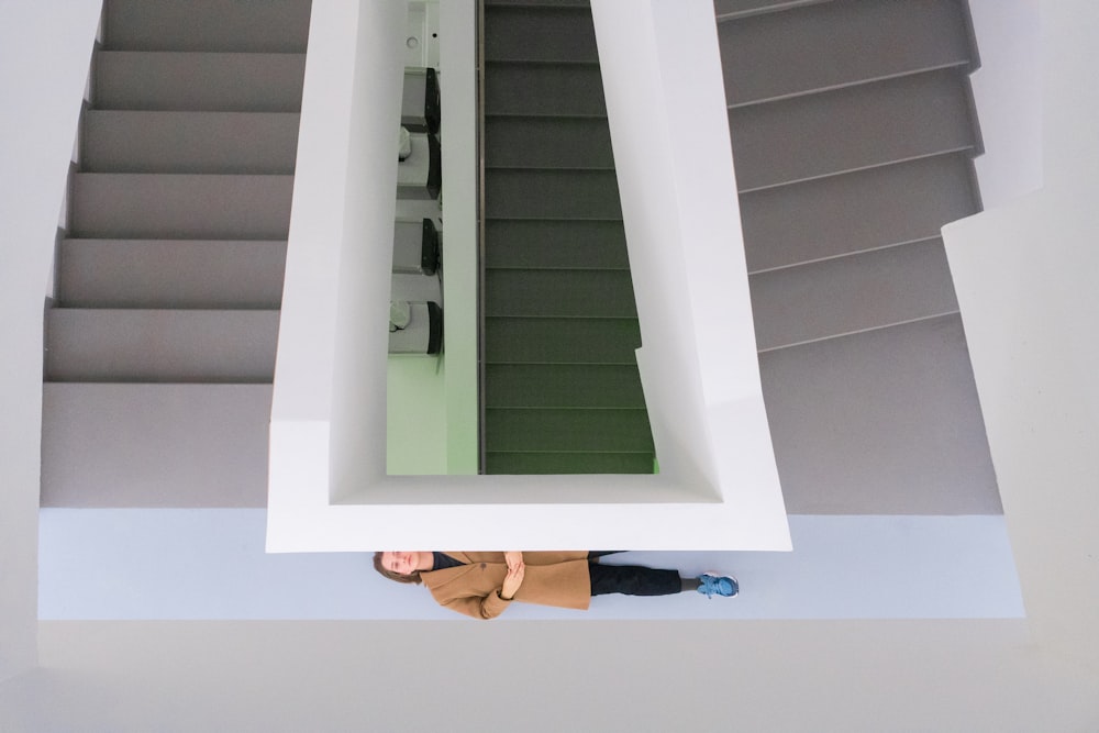 woman in brown coat standing beside stairs balustrade