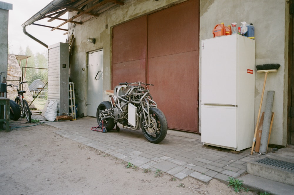 motocicleta nua cinza e branca estacionada em frente ao galpão