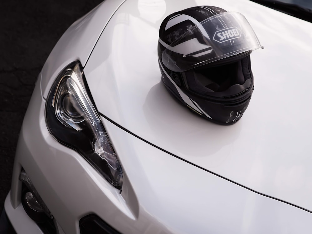 black and white Shoei full-face helmet on white vehicle hood