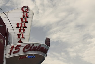 A Gaumont cinema sign with large, bold red letters stands against a cloudy sky. The words '15 Cinémas' and 'IMAX' are visible, indicating multiple screening rooms and IMAX facilities.