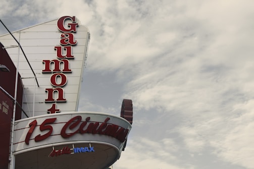 A Gaumont cinema sign with large, bold red letters stands against a cloudy sky. The words '15 Cinémas' and 'IMAX' are visible, indicating multiple screening rooms and IMAX facilities.
