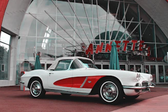 A vintage car parked beside a retro diner, with a model wearing a retrovibe jacket leaning on the hood.