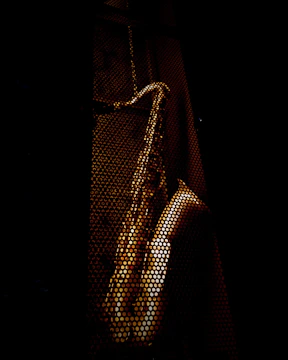 Dynamic shot of a wooden saxophone with dark shadows and orange highlights, set against a black backdrop with parallax effect.