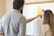 Two people are standing in front of a whiteboard covered with colorful sticky notes. One person is pointing at the notes, suggesting a collaborative work or brainstorming session.