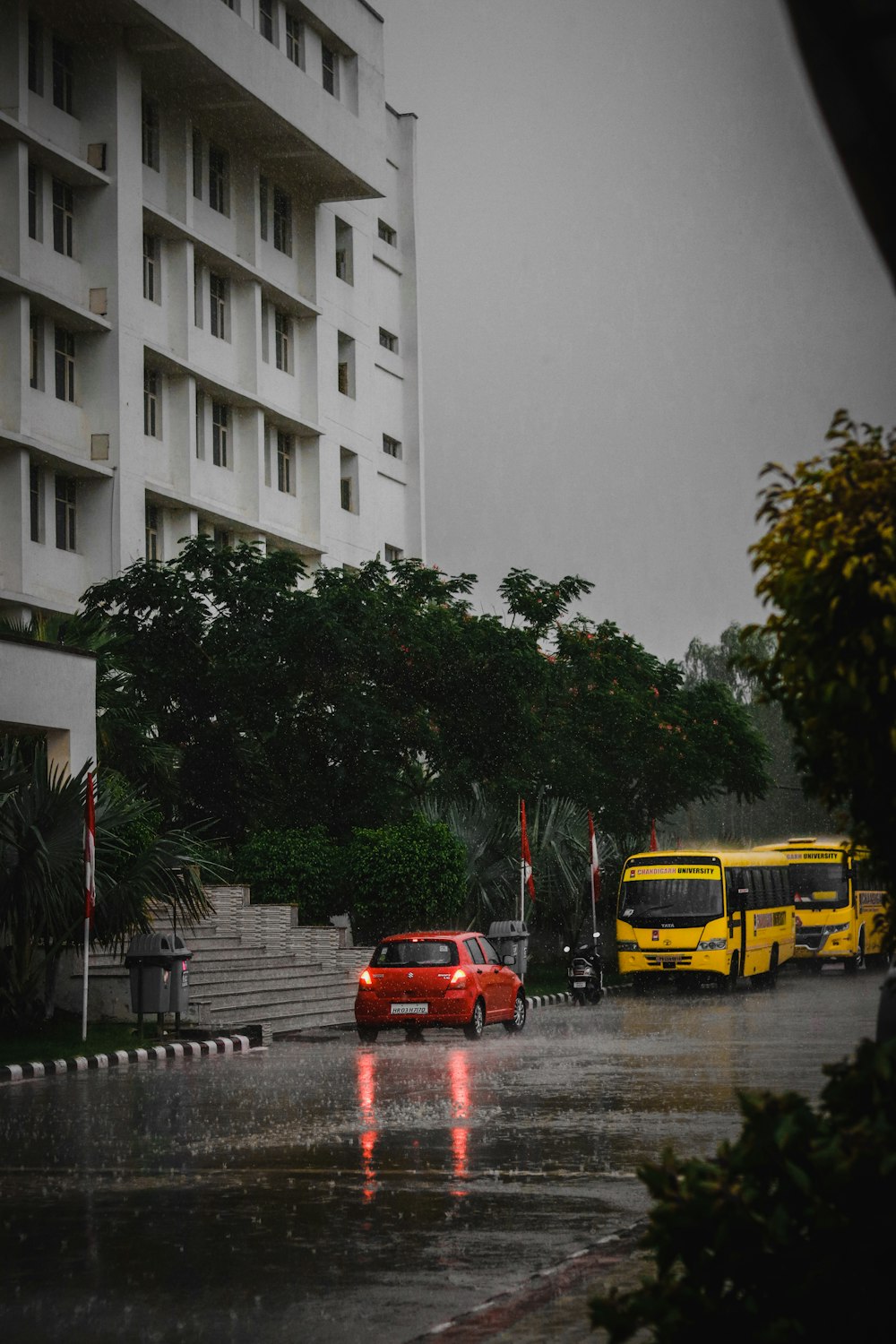 red vehicle and yellow bus on road