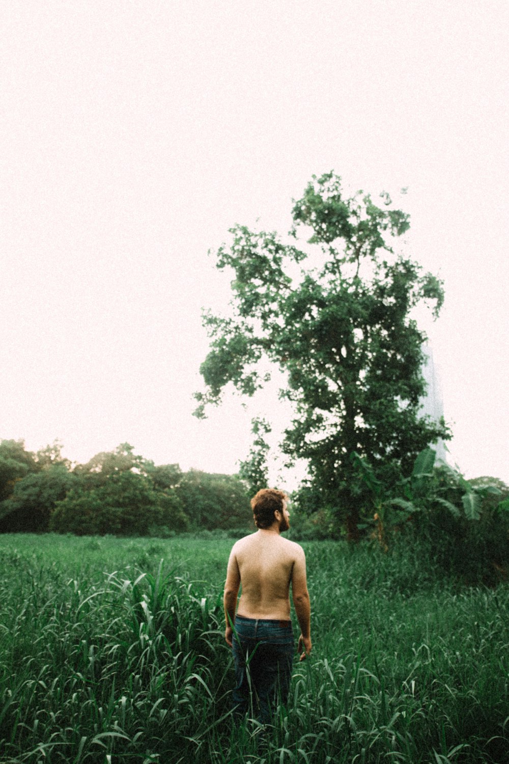 topless man standing near grass field during daytime