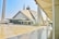 A large, modern mosque with a distinctive geometric design and a blend of traditional and contemporary architectural elements. Tall minarets flank the mosque, and there is a spacious courtyard with people walking around.
