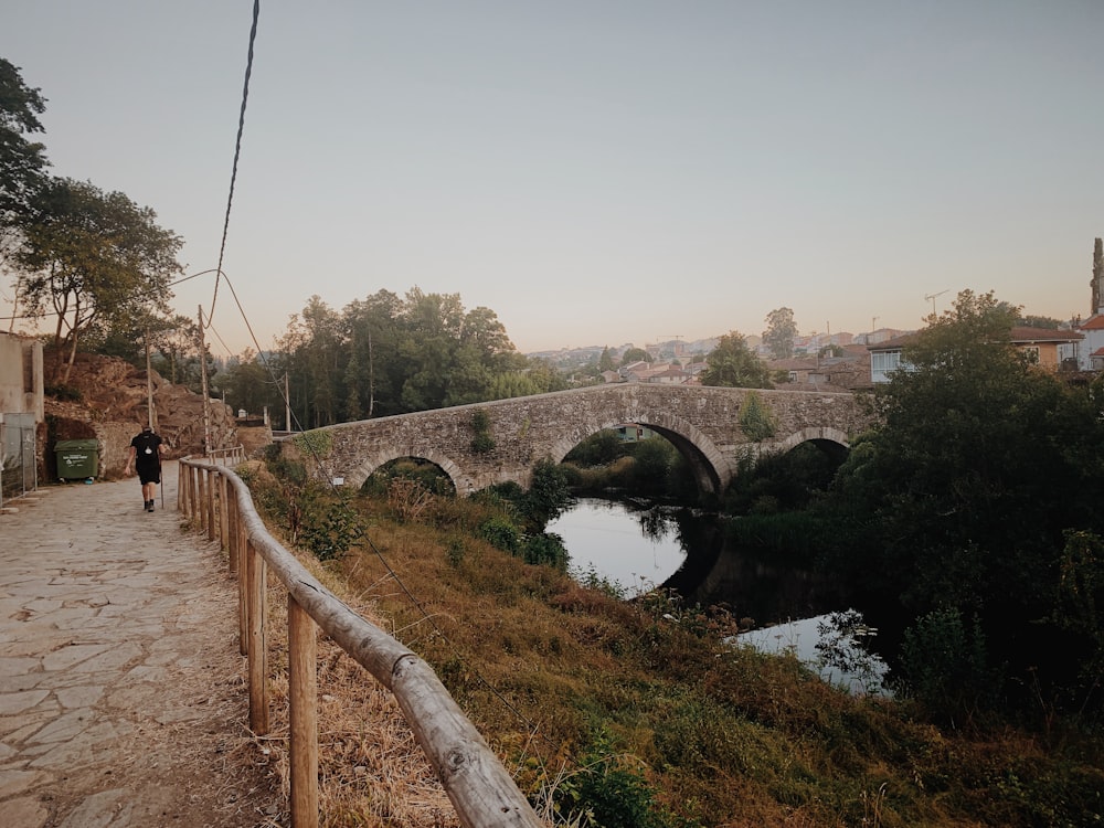 person walking on road beside river during daytime