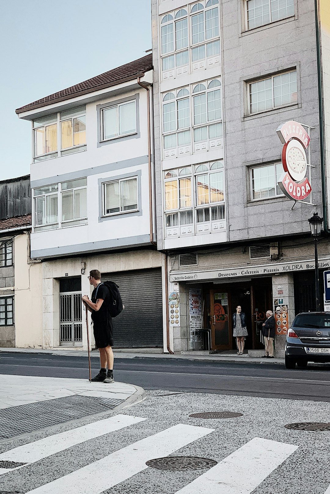 man standing on road beside concrete building during daytime