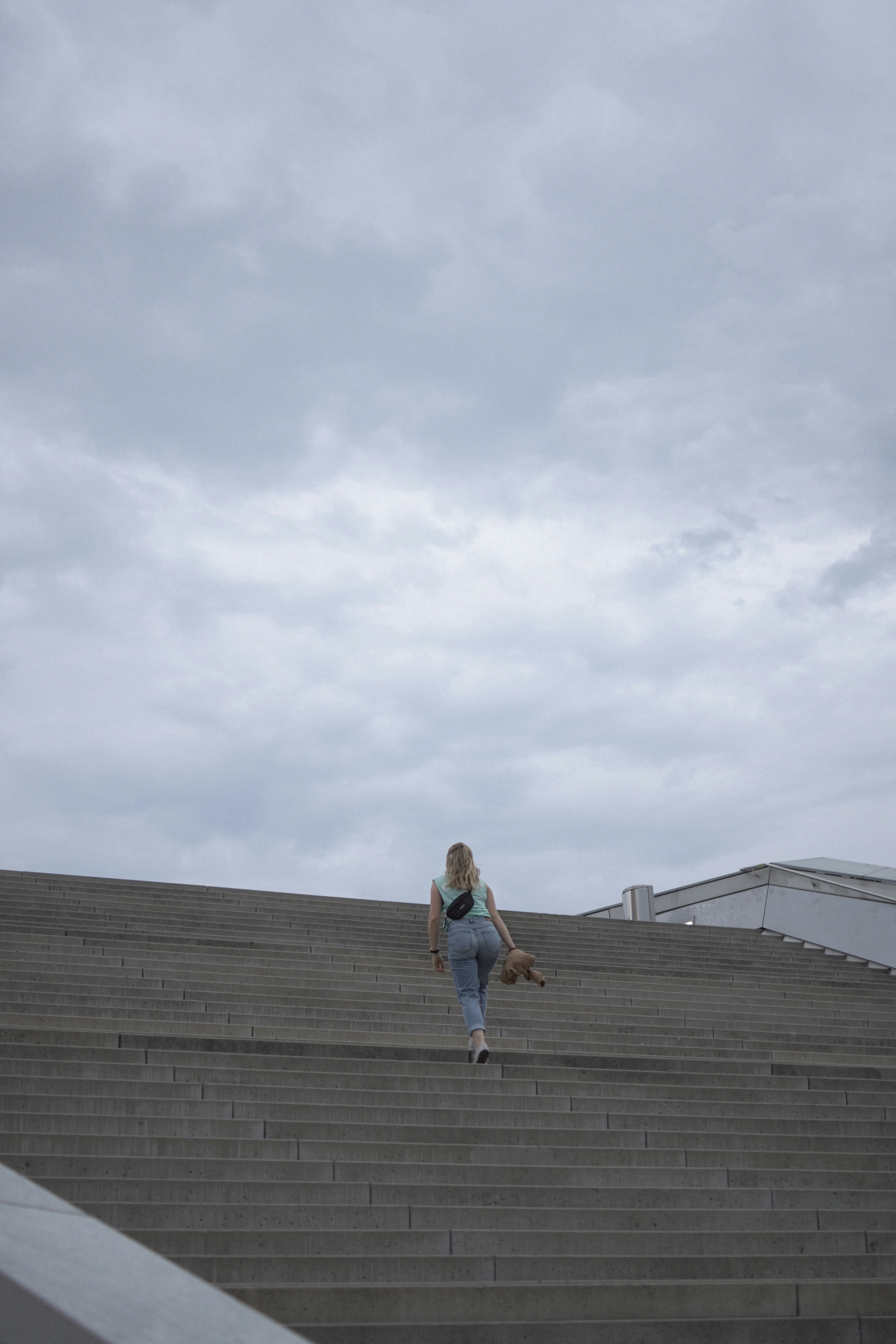 Woman in blue tank top and blue denim shorts walking on brown wooden dock during daytime