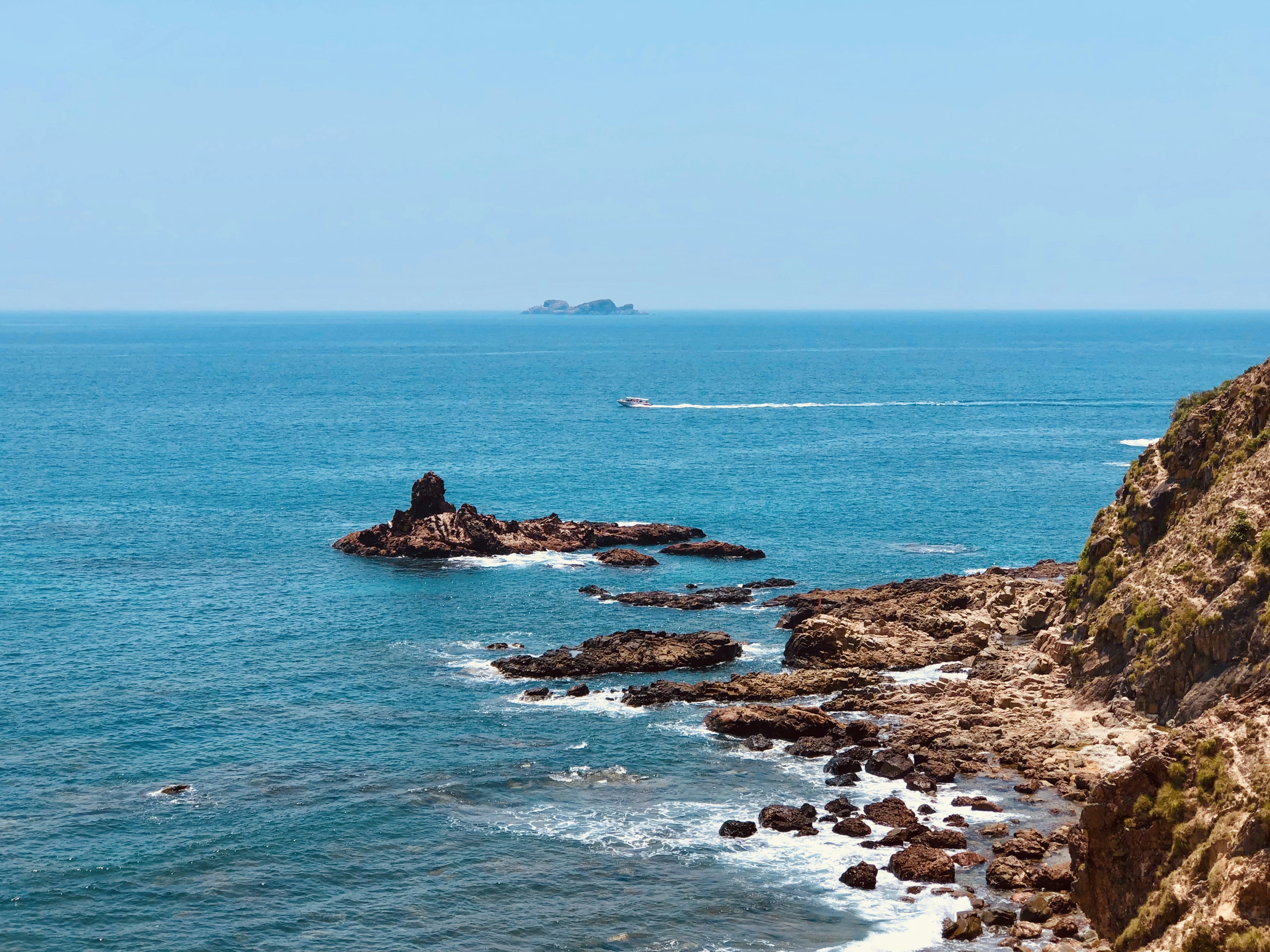 motorboat sailing at sea near rocky shore