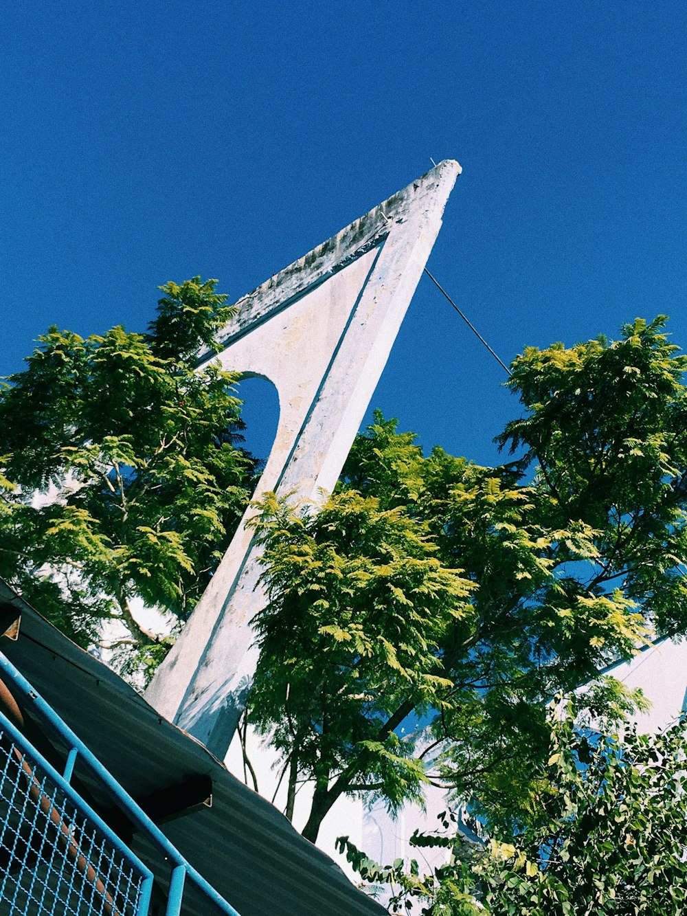 a tall white monument sitting next to a lush green tree