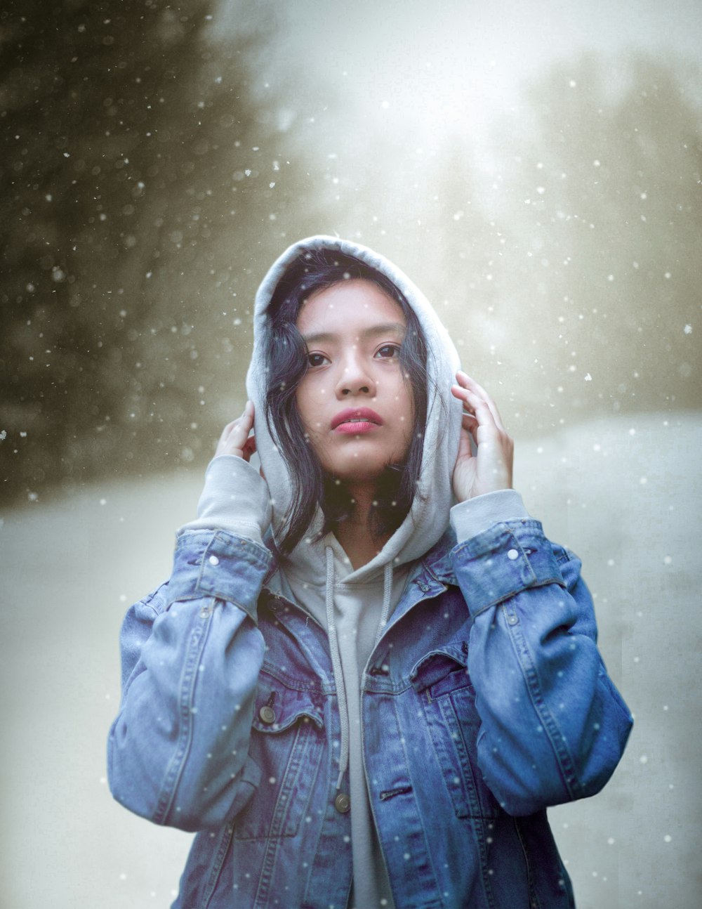 woman standing and wearing blue denim hooded jacket