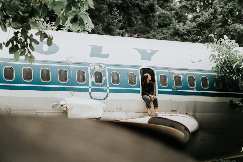 person sitting on airplane door during daytime