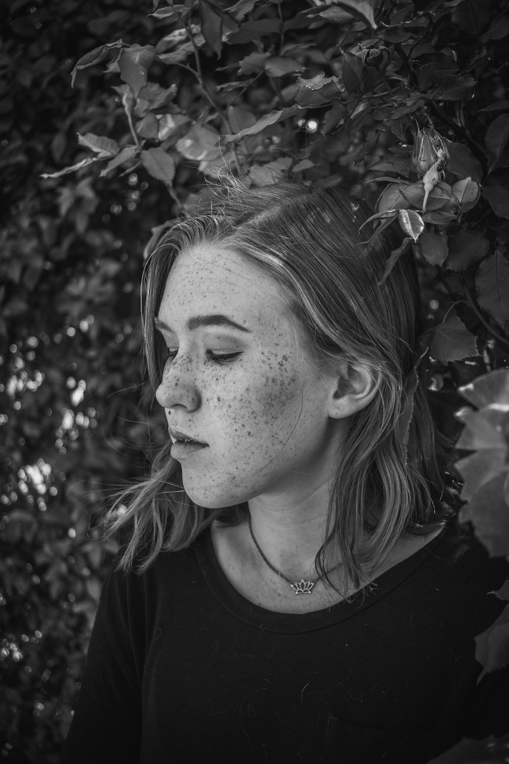 grayscale photo of woman near plants