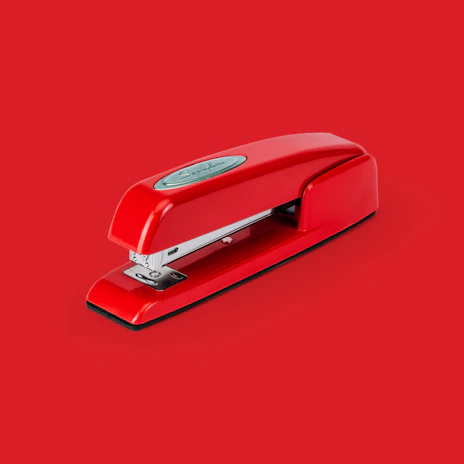 A sleek red stapler resting on a clean white desk, with a subtle crimson background.