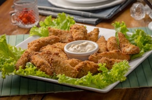 A colorful spread of sides and sauces arranged around a basket of crispy chicken tenders.