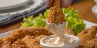 person dipping fried cuisine on dip