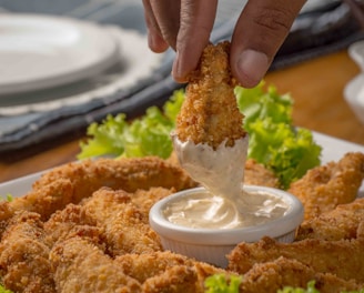 person dipping fried cuisine on dip