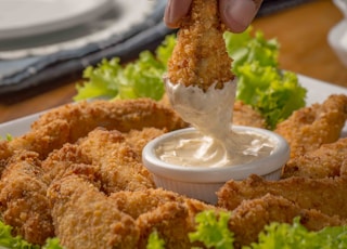 person dipping fried cuisine on dip