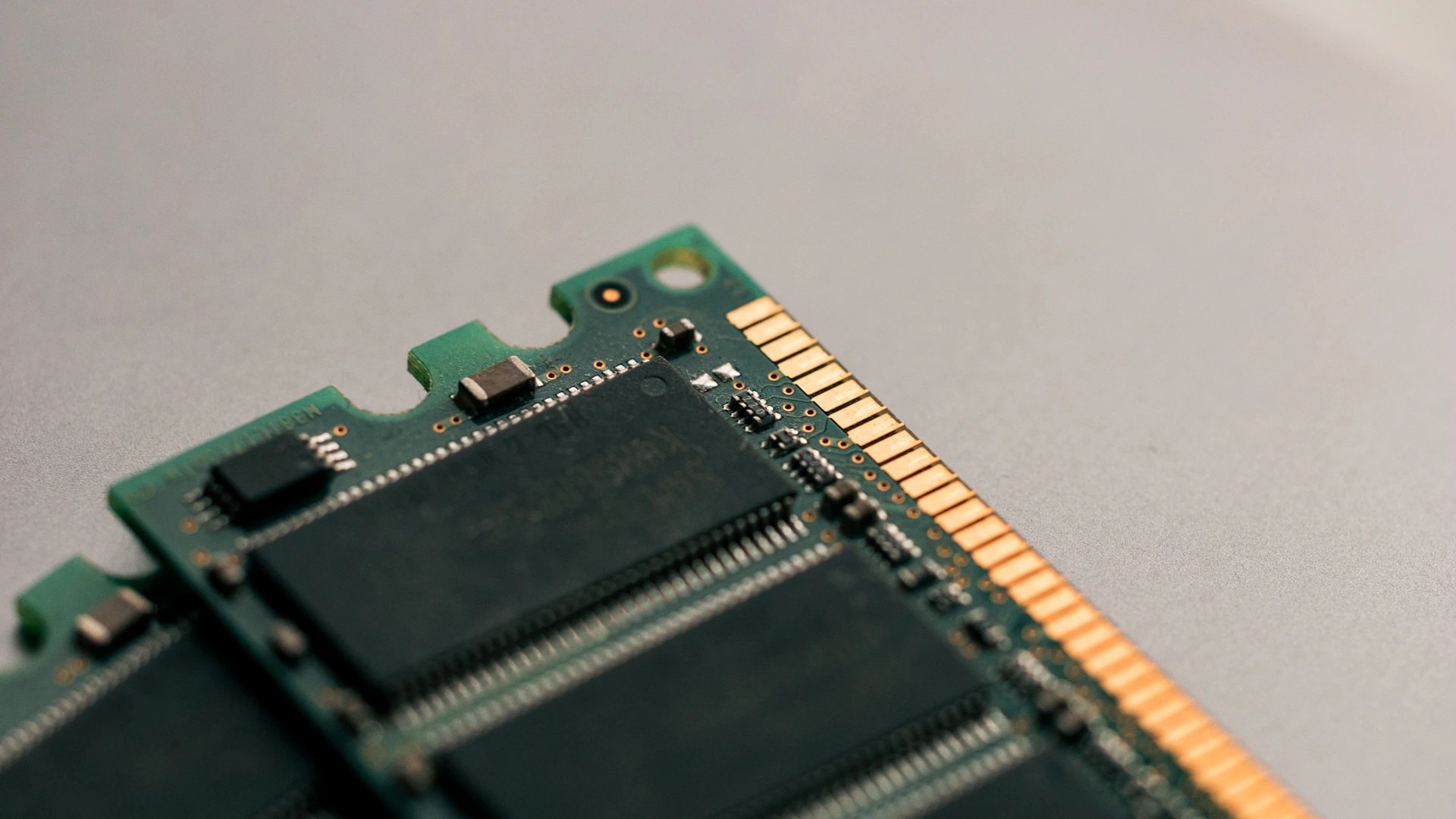 Close-up of memory chips and gold edge contacts on a computer memory module.