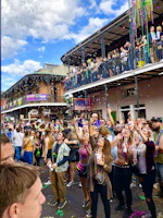 A joyful crowd dancing at a Mardi Gras parade with vibrant costumes and beads.