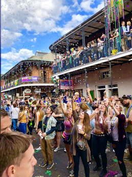 A lively street scene in New Orleans during a jazz festival, with colorful decorations and musicians playing.