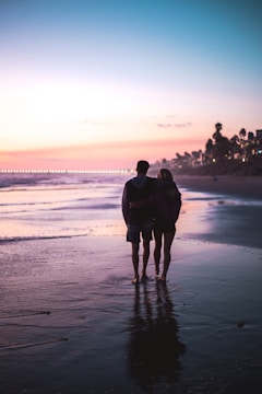 An older couple enjoying a sunset walk on the beach, symbolizing peaceful retirement.