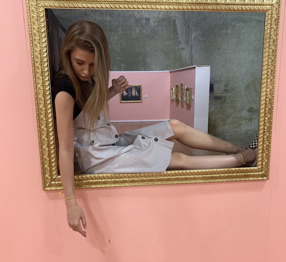 woman sitting on gray and brown painting frame