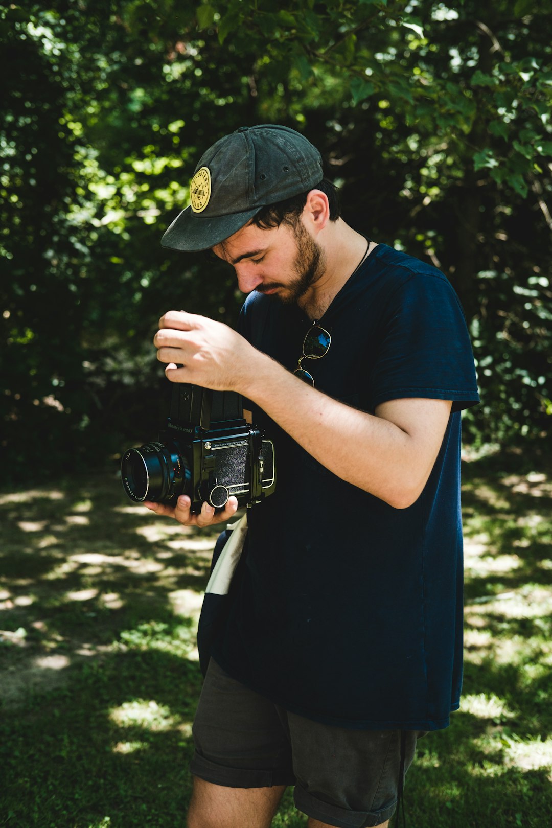 man in black shirt standing outside and holding DSLR camera