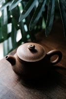 A rustic teapot with an earthy matte finish sitting on a wooden table.